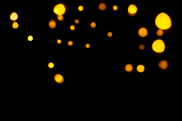 Fototapeta na wymiar Gold bokeh on dark background. Defocused golden lights. New Year, Christmas background, abstract texture