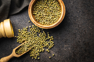 Dried green peppercorn. Dry green pepper spice in scoop on black table.