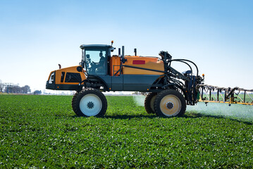 Obraz premium Aerial image of tractor spraying soil and young crop in springtime in field.