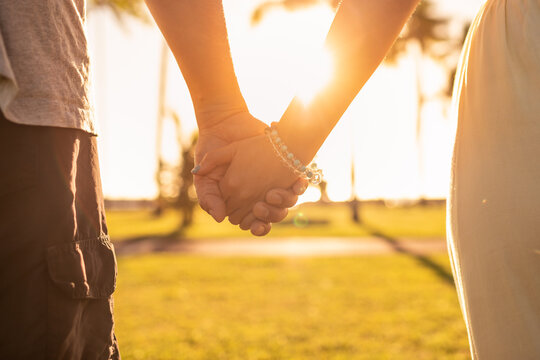 couple holding hands on sunset background 
