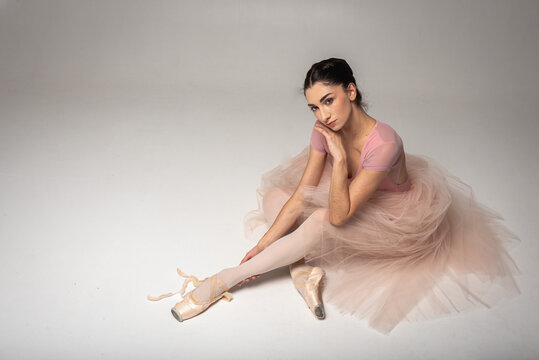 Tired ballerina sitting on a light background background
