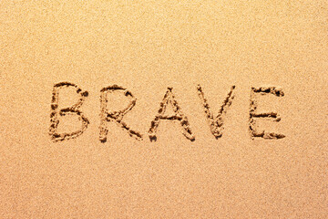 Brave word abstract written in the sand beach. Having courage motivational message