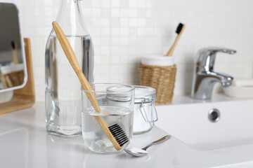 Cleaning a toothbrush with white vinegar, water and baking soda solution on the bathroom sink. Hygiene and healthy lifestyle.