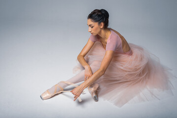 Tired ballerina sitting on a light background background