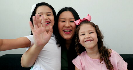 Obraz premium Asian mother waving hello to camera holding multi-ethnic little girls