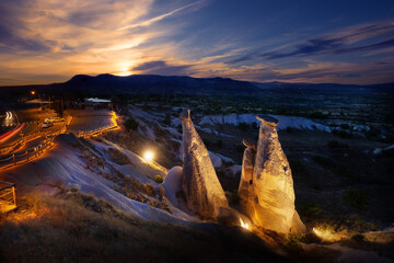 View of symbol of Cappadocia fairy chimneys illuminated by lanterns at sunset