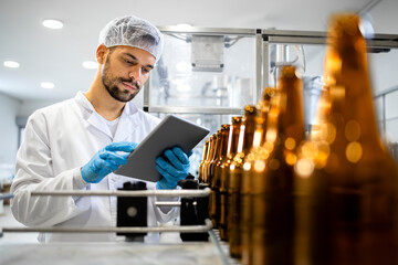 Bottled beer beverage production and factory worker controlling process on tablet computer.