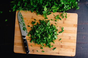 Chopped Fresh Herbs on a Bamboo Cutting Board: A pile of chopped mint, cilantro, and parsley on a wood cutting board