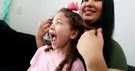 Asian mother interaction with little daughter. mom and small daughter together playing with hair