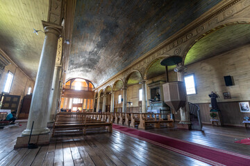 Innenansicht einer alten Holzkirche auf Chiloe samt eines hölzernen Altars, Holzdielen, und einem...