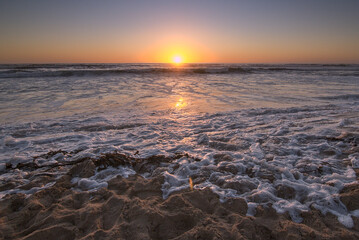 puesta de sol con las olas rompiendo en la orilla de la playa