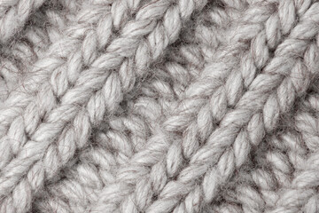 light knitted fabric woolen background - grey, beige, white. The structure of the fabric with a natural texture. Knitting pattern from wool. Winter clothes, scarf, close-up. Wallpaper, macro