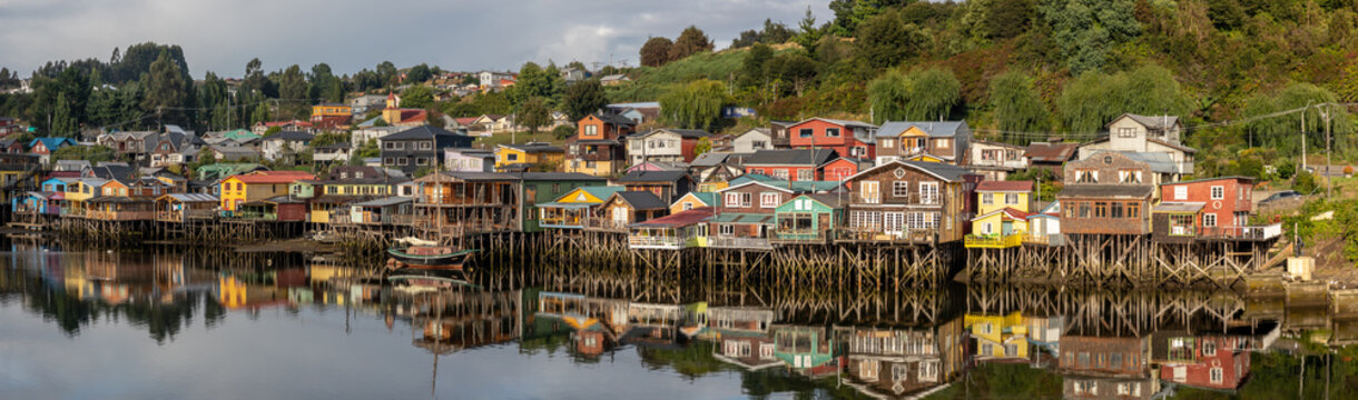Ein Panorama der Stadt von Castro auf Chilo&eacute;, mit den bunten, h&ouml;lzernen Stelzenh&auml;user, welche sich im seichten Wasser spiegeln