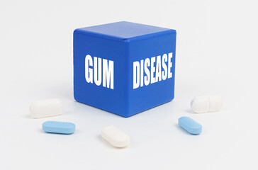 On a white surface are pills and a blue cube that says - GUM DISEASE
