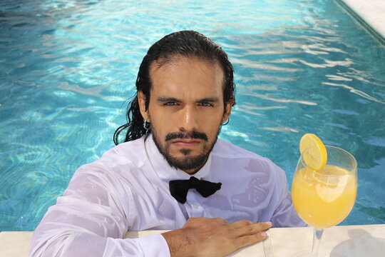Attractive ethnic man getting wet with elegant clothes on