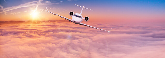 Private jet plane flying above clouds in beautiful sunset. Shot from front view