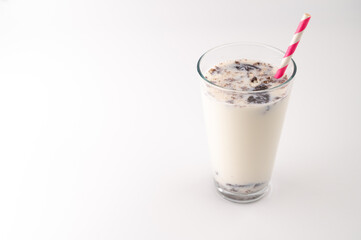 Milk with chocolate cream cookies in a glass with a pink straw on an isolated white background. Copy space.