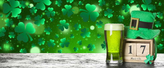 Leprechaun's hat, calendar and glass of beer on table against green background. St. Patrick's Day celebration