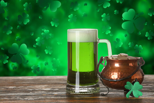 Glass of beer and pot with coins on table against green background. St. Patrick's Day celebration