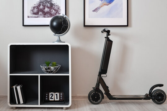 Stylish interior of minimalist room with electric scooter, shelf unit and decor