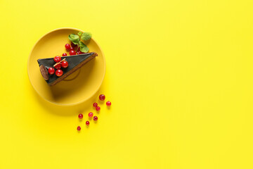 Plate with delicious piece of chocolate cake and cranberries on yellow background