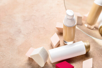 Different makeup sponges and foundation on color background, closeup