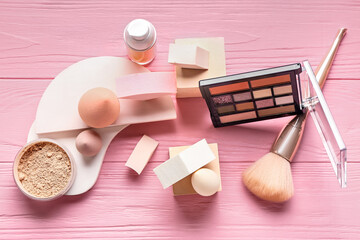 Composition with different makeup sponges and cosmetics on pink wooden background