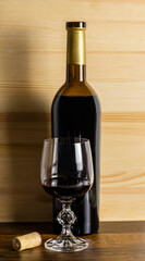 Bottle of red wine and glass of bulk wine on a wooden background