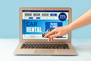 Female hand and laptop with open page of car rental site on color background