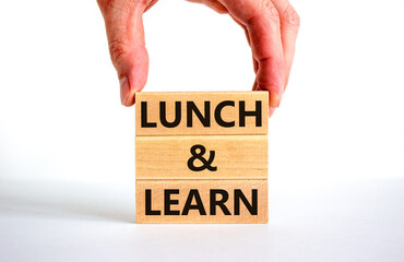 Lunch and learn symbol. Concept words Lunch and learn on wooden blocks. Beautiful white table white background. Businessman hand. Copy space. Business, educational and lunch and learn concept.