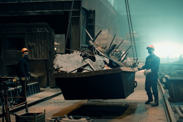 Workers at metallurgical plant. Working with scrap metal. Metal manufacturing and recycling factory.