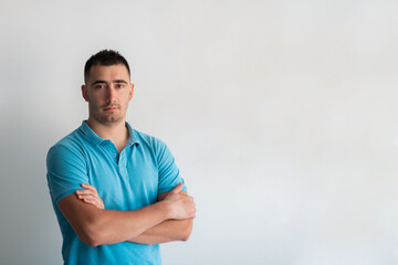 Formal business male portrait. A confident successful casual businessman or manager stands in front of a white background, arms crossed, looking directly at the camera and smiling friendly. High