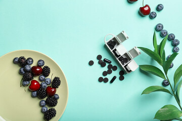 Activated carbon in capsules, pills and berries on color background