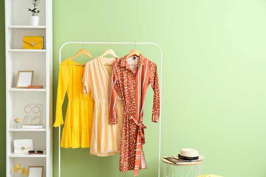 Hanger with dresses and shelf unit with accessories near color wall