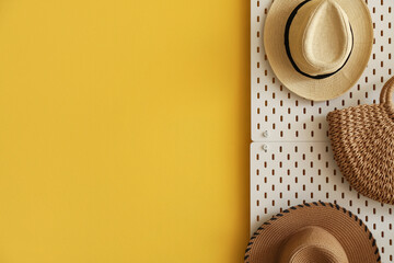 Pegboard with stylish hats and bag hanging on yellow wall