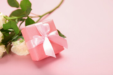 Beautiful gift box and flowers on pink background