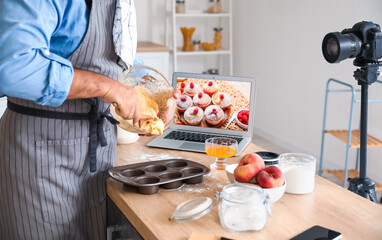 Handsome man preparing peach muffins and recording video tutorial in kitchen
