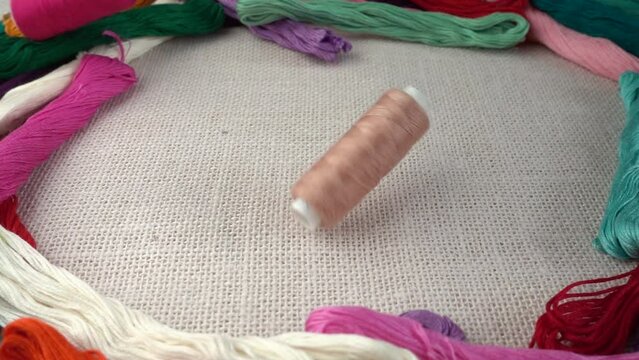 Falling multicolored spools on burlap against the background