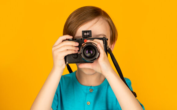 Little boy on a taking a photo using a vintage camera. Child in studio with professional camera. Boy using a cameras. Baby boy with camera. Cheerful smiling child holding a cameras