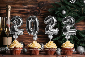 Christmas cupcakes with balloon numbers on wooden background