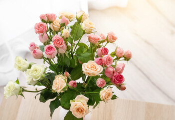 Bouquet of beautiful roses on wooden table in light room