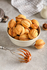 Bowl of walnut shaped cookies with boiled condensed milk on grey background