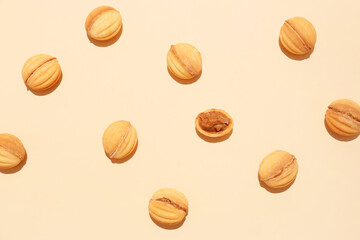 Many tasty walnut shaped cookies with boiled condensed milk on color background