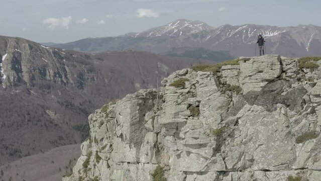 Hiker approaching steep rock peak on top of mountain