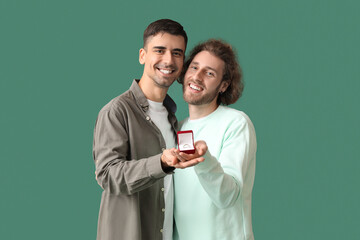 Happy engaged gay couple on green background