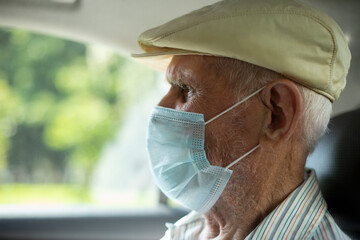 An elderly man in a taxi. An old man in a medical mask in transport. A man who is 91 years old. Russian old man. © Олег Копьёв
