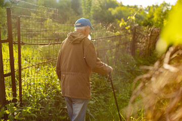 An old man with a walking stick. A Russian old man in the countryside.