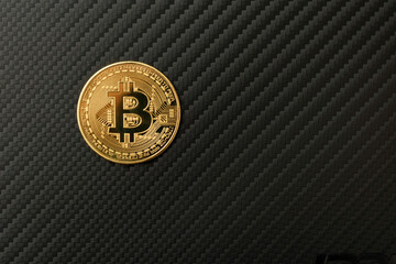 yellow metal bitcoin on black carbon overlay background