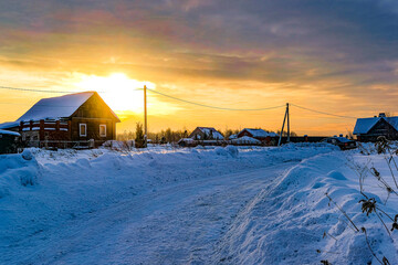 country winter landscape with the image of a village at sunset