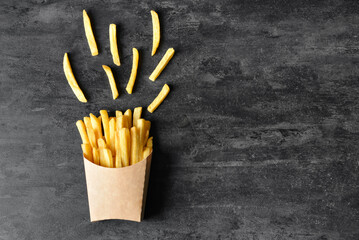 Paper box with tasty french fries on black background